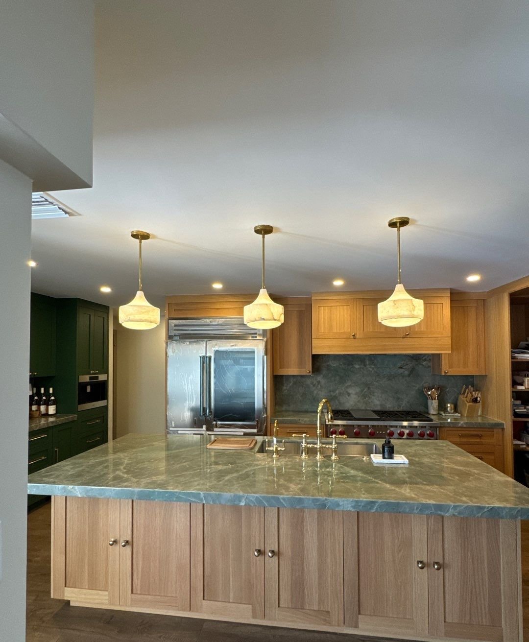 White oak kitchen island with quartzite countertop and brass bridge faucet in Saint Petersburg