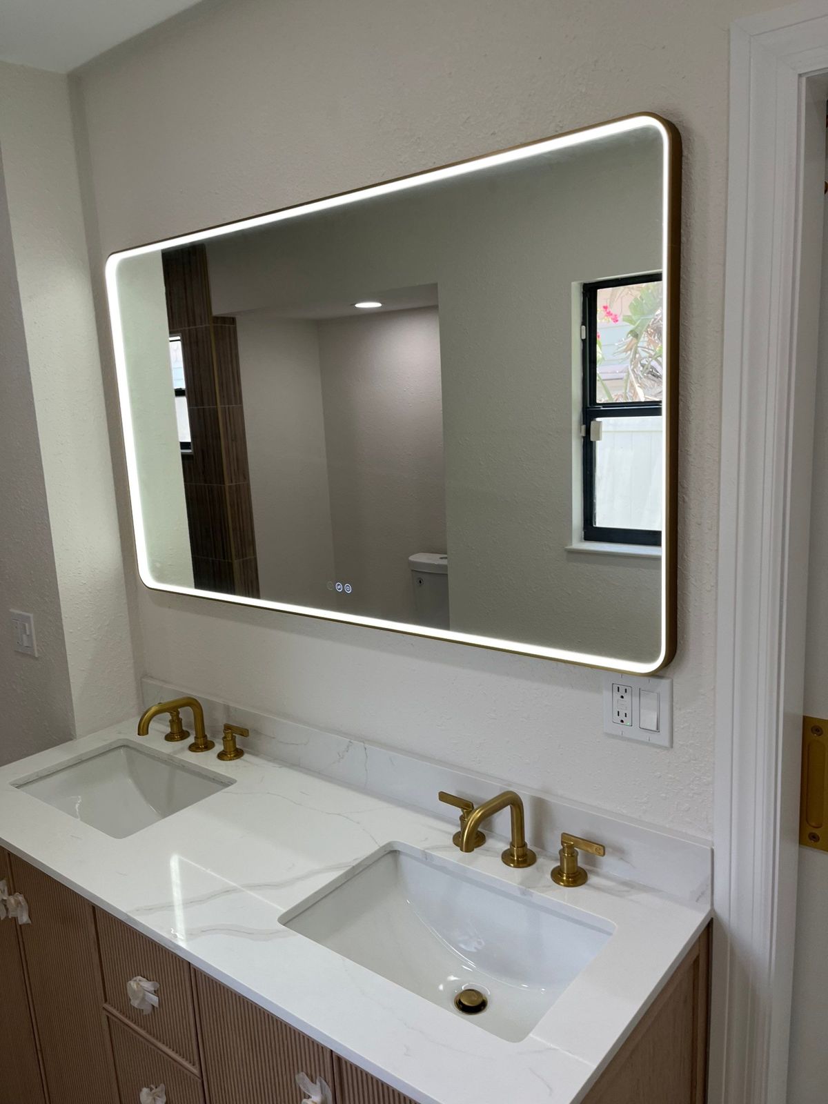 Double vanity with quartz top, undermount sinks and brass faucets in a Tampa master bath