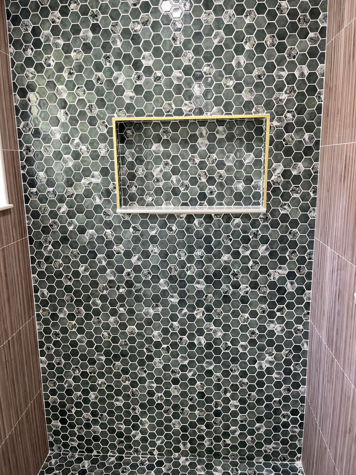 Green hexagon mosaic shower wall with brass-trimmed recessed niche